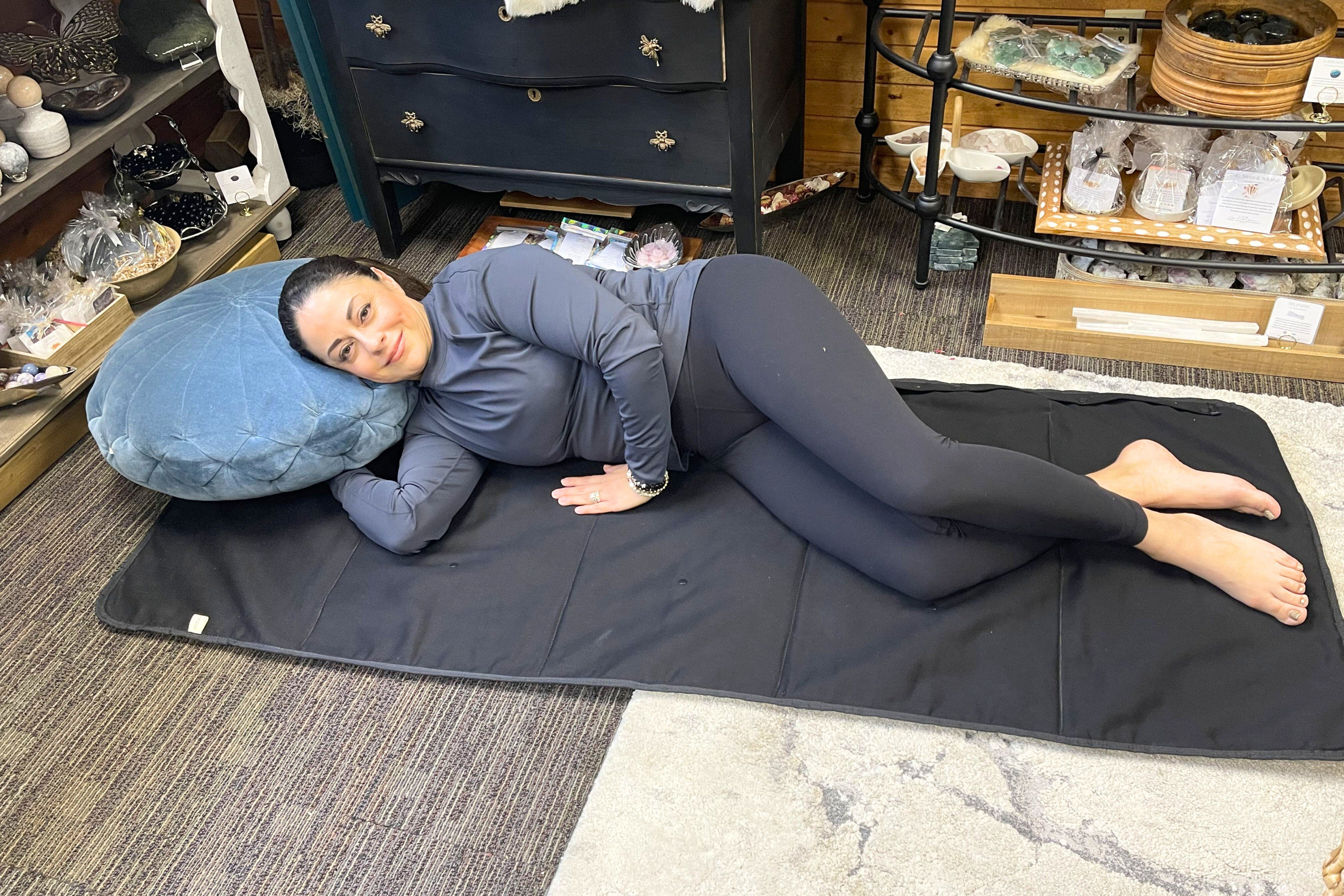 Woman using the Sentient Light Element PEMF therapy mat for a full-body session